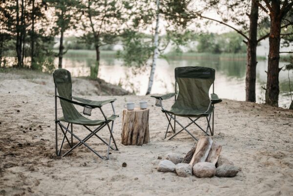 Peaceful camping spot with chairs by a lake, perfect for relaxation and nature lovers.